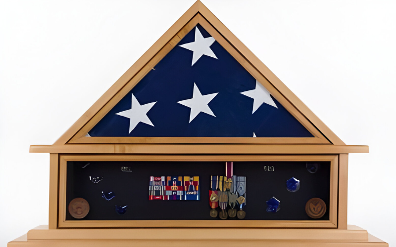 A folded American flag displayed ceremoniously in a wooden triangular shadow box case.